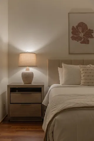 a bedroom with a bed and a lamp on dresser