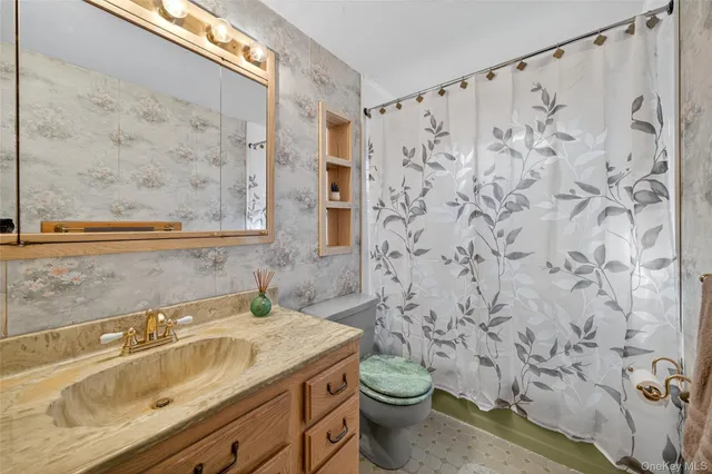 a bathroom with a granite countertop sink and a toilet
