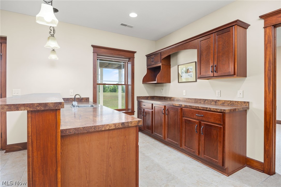 6925 River Styx Road Medina, OH 44256 - Photo 36 of 49 Wet bar featuring a sink, extensive wood-finish cabinetry, and solid surface countertops