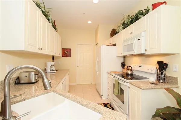 a kitchen with a sink a stove and white cabinets