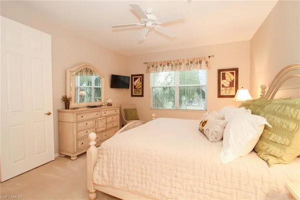 a bedroom with a bed a window dresser and flat screen tv