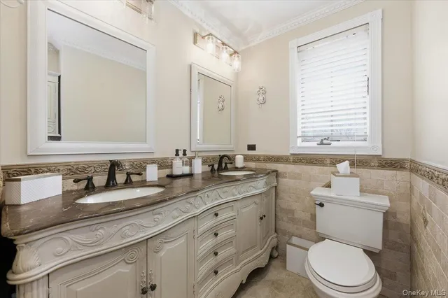 a bathroom with a granite countertop toilet a double vanity sink and mirror