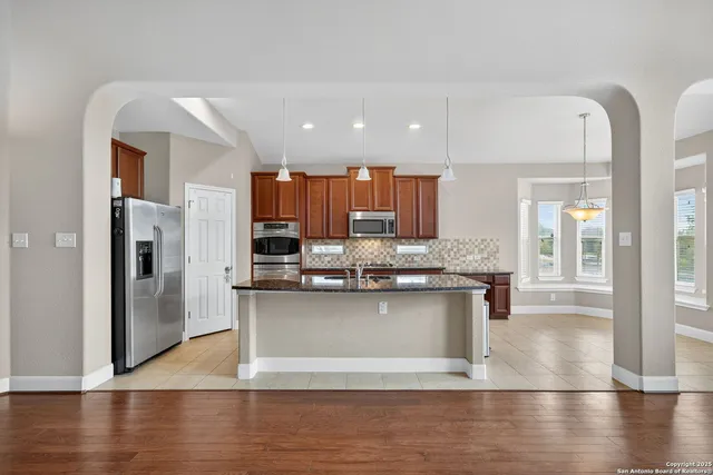 a view of a kitchen with kitchen island a counter top space a sink stainless steel appliances and cabinets