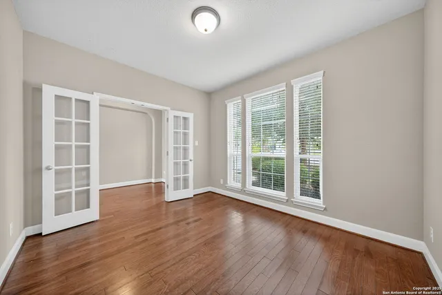 an empty room with wooden floor and windows
