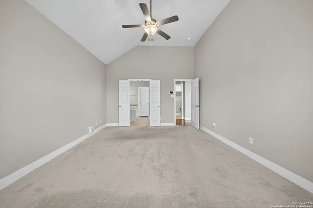 an empty room with chandelier fan and windows