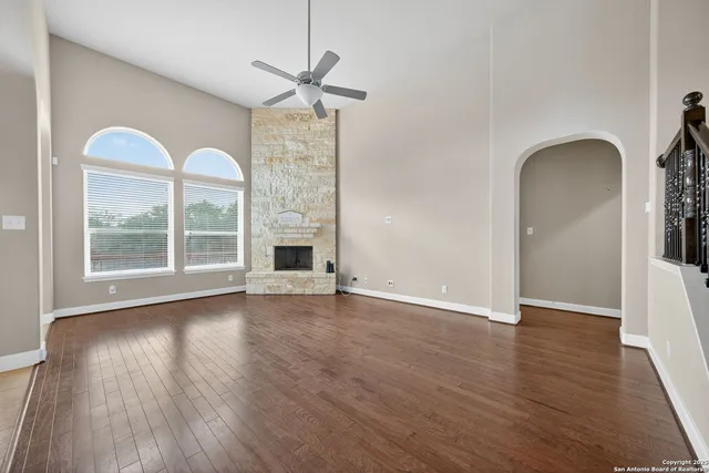 an empty room with wooden floor fireplace and windows
