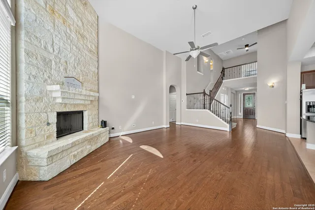 a view of an empty room with wooden floor fireplace and a window