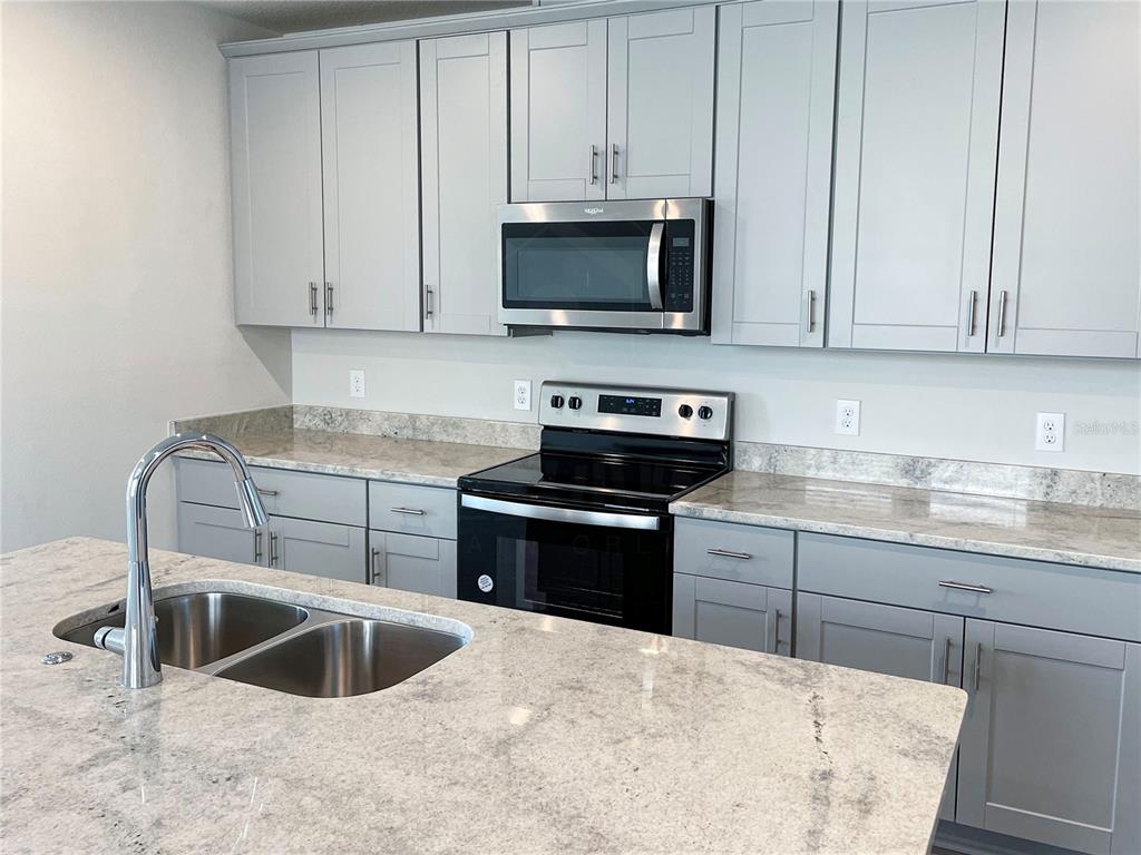 902 Rivers Crossing Street Clermont, FL 34714 - Photo 3 of 26 a kitchen with granite countertop a sink and a stove top oven