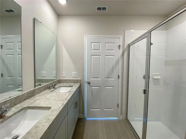 a bathroom with a granite countertop sink a mirror and a shower