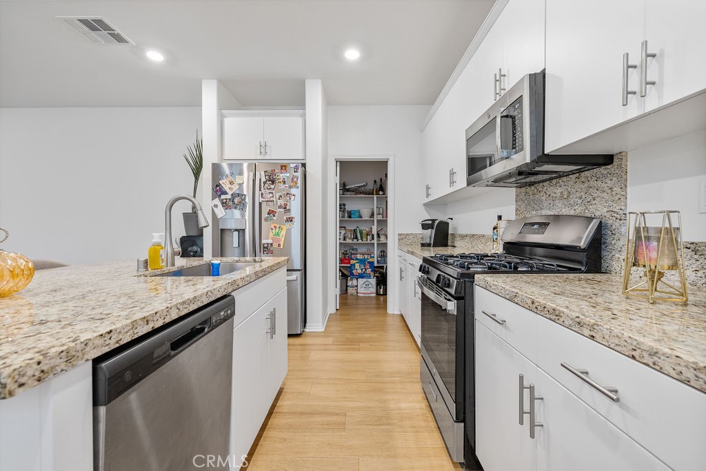 2522 Gunner Ridge Way Rialto, CA 92377 - Photo 8 of 40 a kitchen with stainless steel appliances granite countertop lots of counter top space a sink a stove and a wooden floors