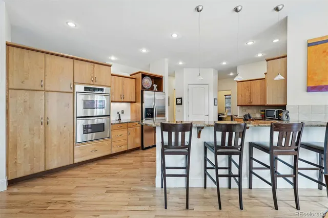 a kitchen with stainless steel appliances kitchen island granite countertop a table chairs sink and cabinets