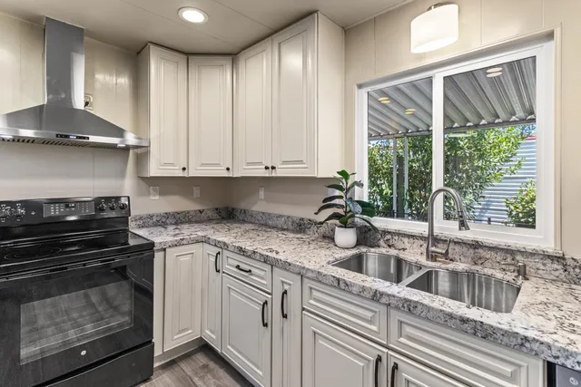 a kitchen with stainless steel appliances granite countertop a stove a refrigerator and a cabinets with wooden floor