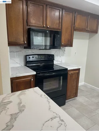 a kitchen with granite countertop a stove top oven microwave and cabinets