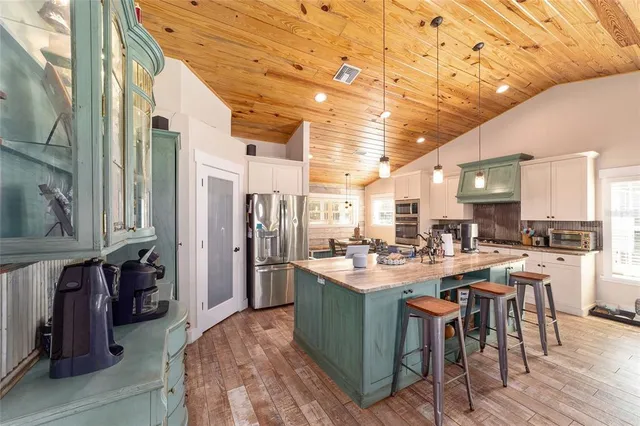 a view of a kitchen with kitchen island stainless steel appliances a sink and living room view