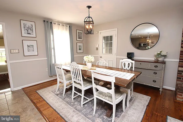 a dining room with wooden floor a chandelier a wooden table and chairs