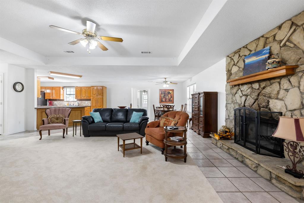 321 Vz County Road 2602 Wills Point, TX 75169 - Photo 12 of 39 Living room featuring light tile patterned floors, visible vents, a raised ceiling, and a stone fireplace