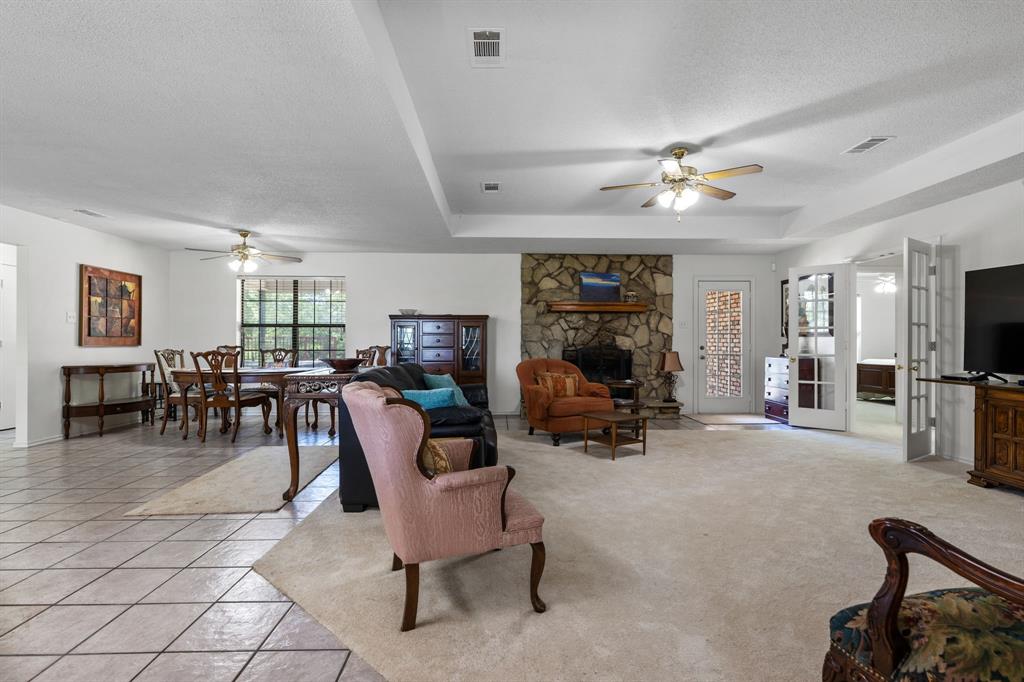321 Vz County Road 2602 Wills Point, TX 75169 - Photo 10 of 39 Living area featuring light tile patterned floors, a raised ceiling, visible vents, a textured ceiling, and a stone fireplace