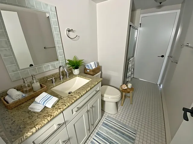 a bathroom with a granite countertop sink mirror vanity and toilet