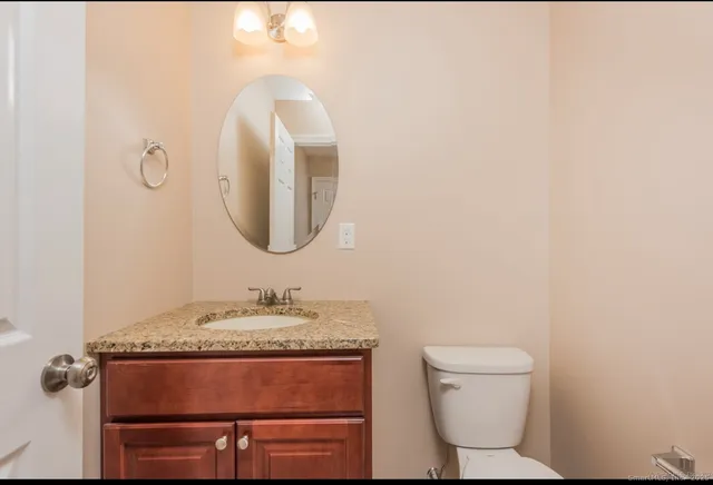 a bathroom with a granite countertop toilet sink and mirror