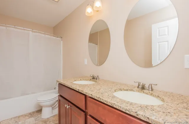 a bathroom with a granite countertop toilet a sink and a mirror