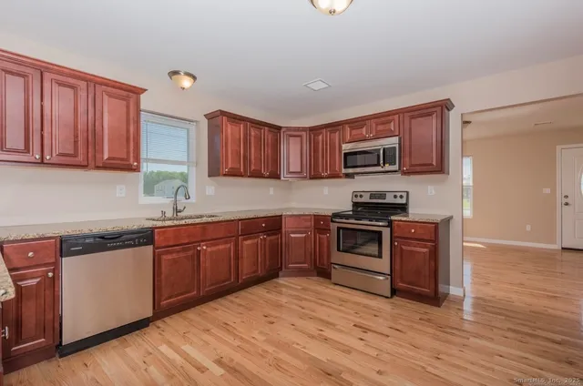 a kitchen with stainless steel appliances granite countertop a stove top oven a sink and dishwasher a oven with wooden floors