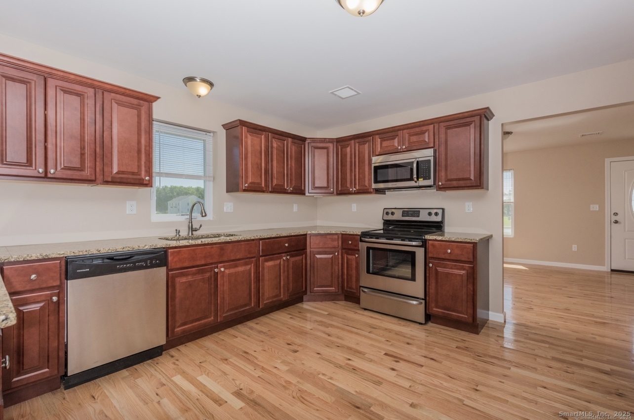 13 Nature Avenue, Unit A Colchester, CT 06415 - Photo 6 of 34 a kitchen with stainless steel appliances granite countertop a stove top oven a sink and dishwasher a oven with wooden floors