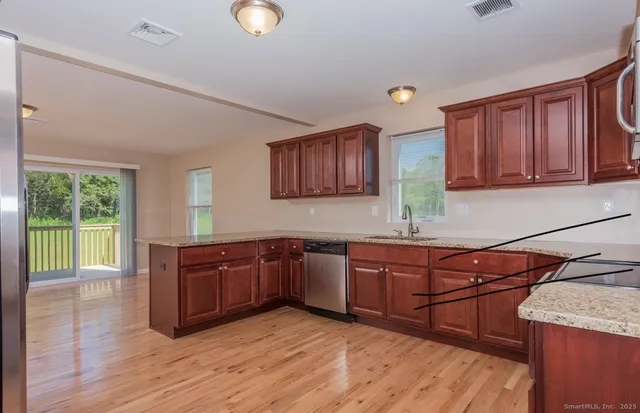 a kitchen with stainless steel appliances granite countertop wooden cabinets a sink and dishwasher with wooden floor