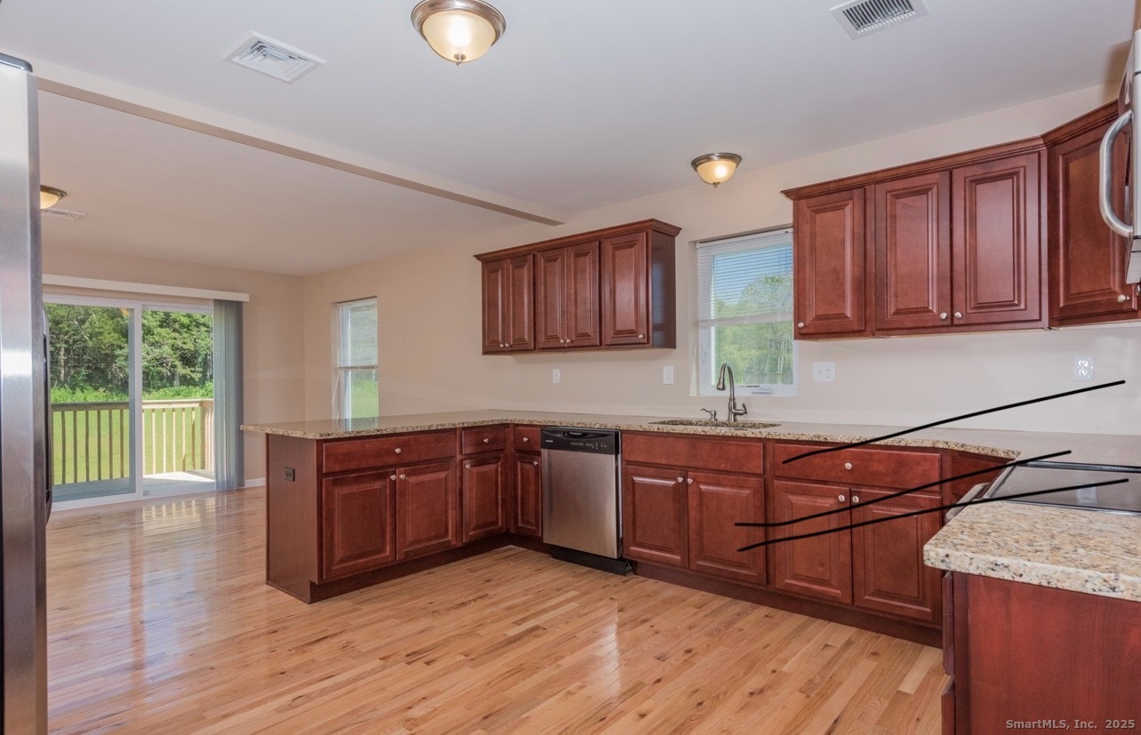 13 Nature Avenue, Unit A Colchester, CT 06415 - Photo 7 of 34 a kitchen with stainless steel appliances granite countertop wooden cabinets a sink and dishwasher with wooden floor