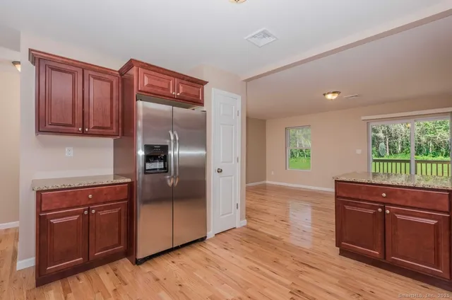 a kitchen with stainless steel appliances granite countertop a refrigerator sink and wooden cabinets