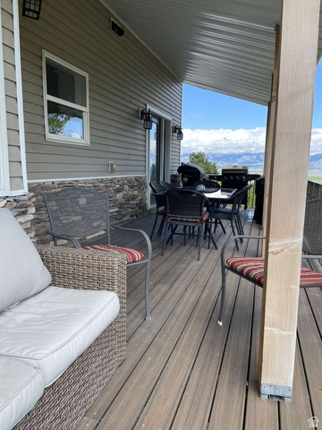 7030 West 2100 North Mendon, UT 84325 - Photo 50 of 67 Covered outdoor deck with composite decking, stone veneer accent wall, siding exterior, and a sliding glass door