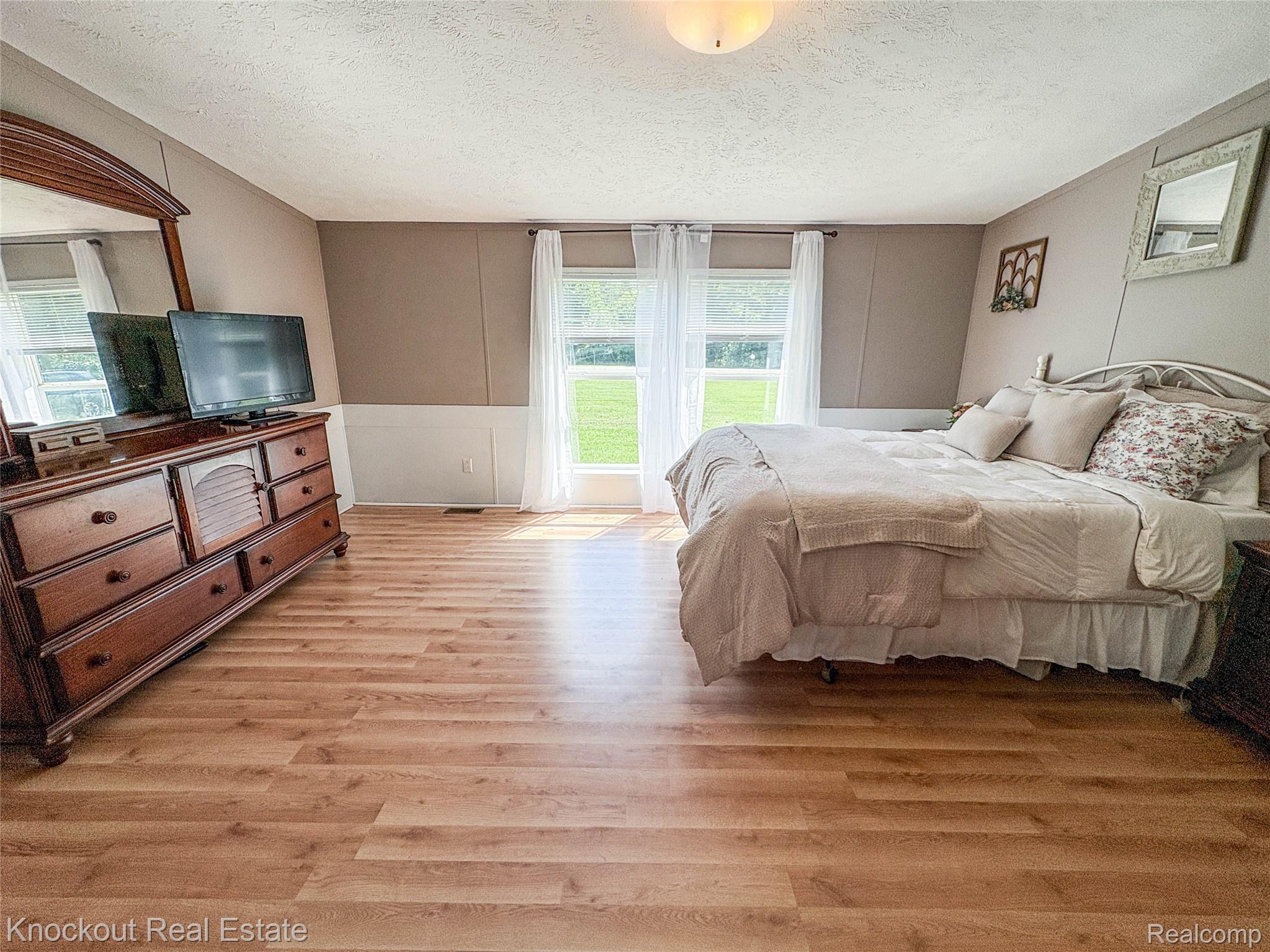 7760 Bell Road Birch Run, MI 48415 - Photo 29 of 68 Spacious room featuring light wood-finish flooring, neutral wall tones with wainscoting, and large windows providing ample natural light