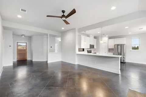 a view of a kitchen and an empty room with wooden floor