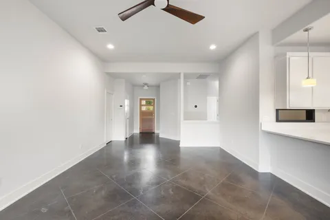 a view of an empty room with wooden floor and a kitchen