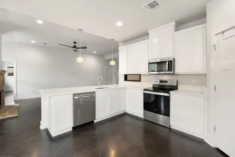 a kitchen with granite countertop white cabinets and stainless steel appliances