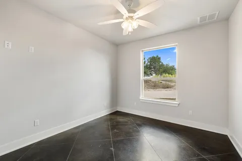 an empty room with a window and a fan