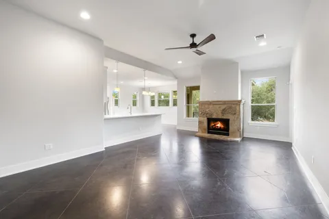 an empty room with wooden floor fireplace and windows