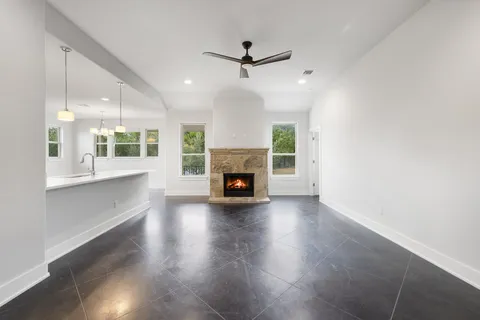 an empty room with wooden floor a fireplace a ceiling fan and windows