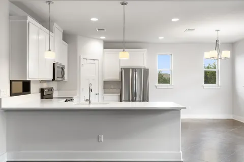 a large kitchen with granite countertop a large counter top a sink stainless steel appliances and cabinets