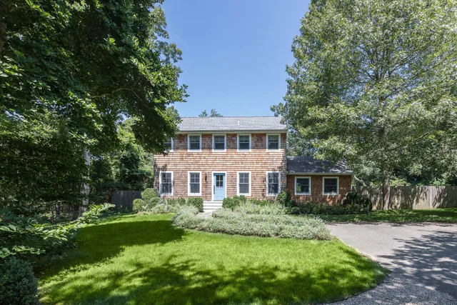 a front view of a house with a yard and green space