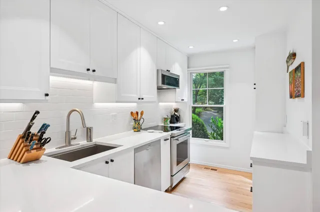a kitchen with a sink appliances cabinets and a window