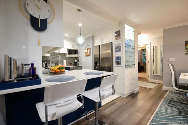 a kitchen with a refrigerator a stove a sink and a dining table with wooden floor