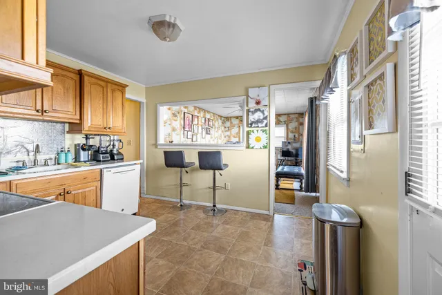a kitchen with stainless steel appliances kitchen island granite countertop dining table chairs and a refrigerator