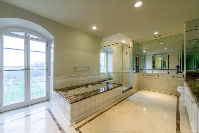 a spacious bathroom with a tub a mirror and a shower