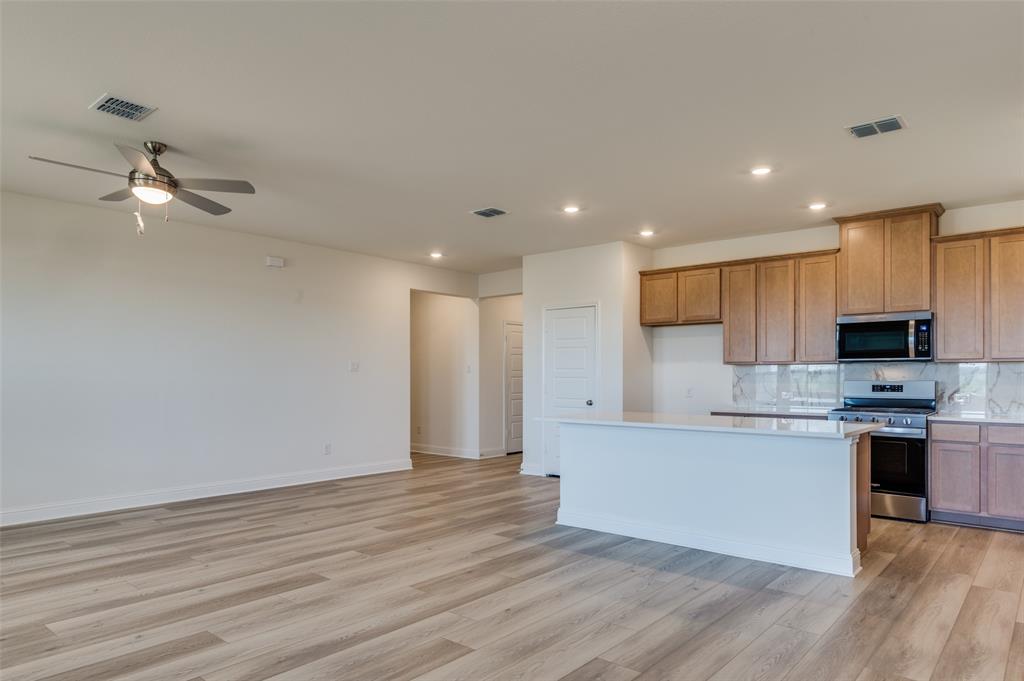 345 Fallbrook Drive Aledo, TX 76008 - Photo 6 of 32 Kitchen with stainless steel appliances, tasteful backsplash, light countertops, light wood finished floors, and a ceiling fan