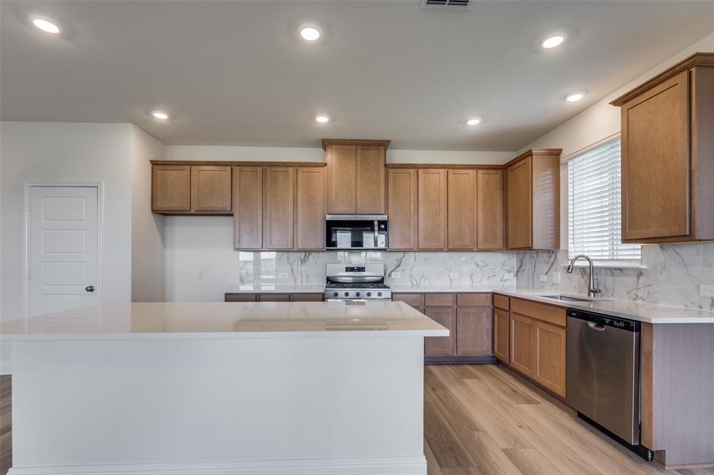 345 Fallbrook Drive Aledo, TX 76008 - Photo 7 of 32 Kitchen with tasteful backsplash, light wood-type flooring, brown cabinetry, appliances with stainless steel finishes, and recessed lighting
