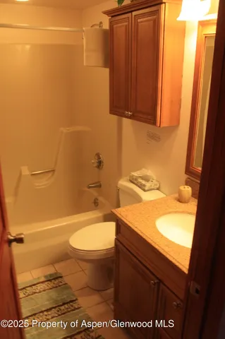 a bathroom with a granite countertop toilet and a sink