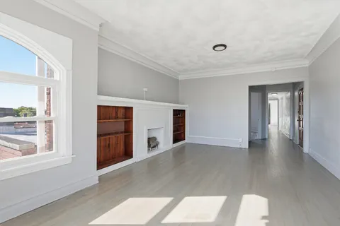 a view of empty room with wooden floor and fireplace