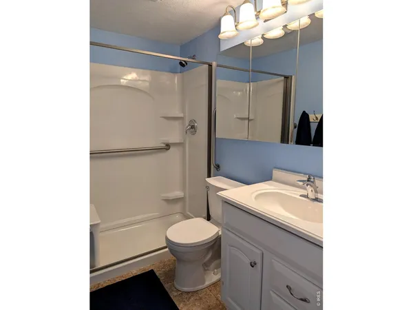 a bathroom with a granite countertop sink mirror vanity and toilet