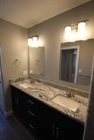 a bathroom with a granite countertop sink and a large mirror