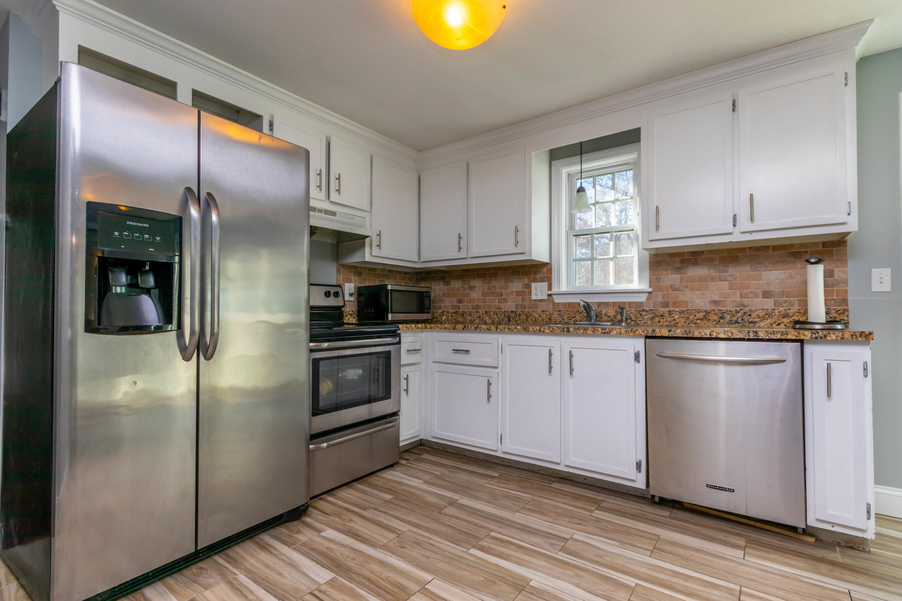 371 Megan Road Hyannis, MA 02601 - Photo 8 of 34 a kitchen with stainless steel appliances granite countertop a refrigerator a stove and a sink with wooden floor